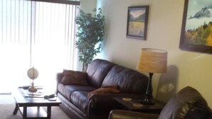 A living room with a leather sofa, a coffee table, a lamp, and a painting on the wall. - Remodeled 2 Bedroom, 2 Bath apartment with Hot Tub.   (belgrade)