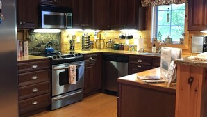A kitchen with wooden cabinets, stainless steel appliances, a microwave, and a stove. - Beautiful cabin close to downtown Boone (Boone)