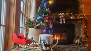 A cozy room with a fireplace, a Christmas tree, a rocking chair, and a mug on a coaster. - Beautiful cabin close to downtown Boone (Boone)