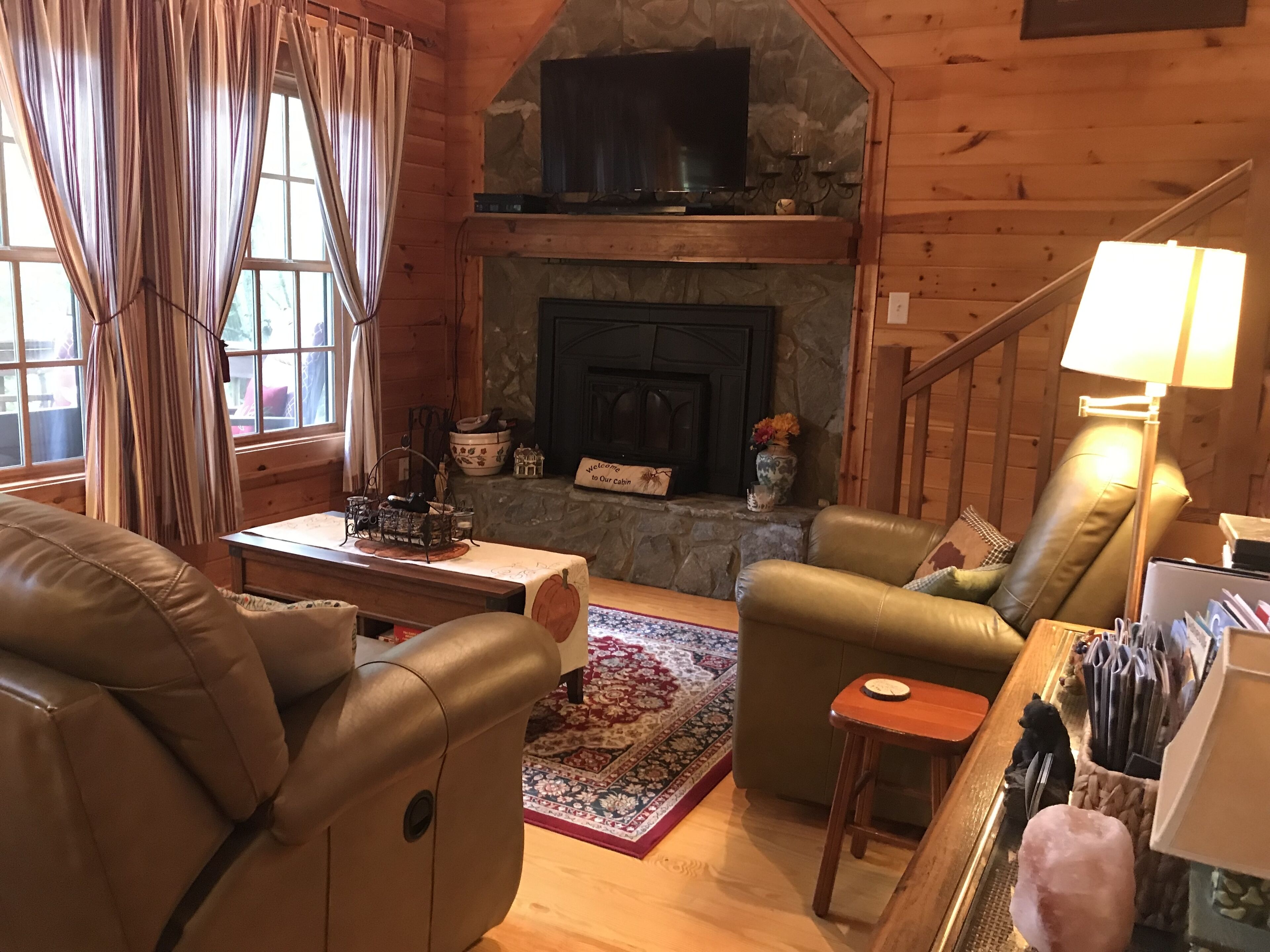 Un intérieur de chalet chaleureux avec une cheminée, des meubles en cuir et un mur en pierre.