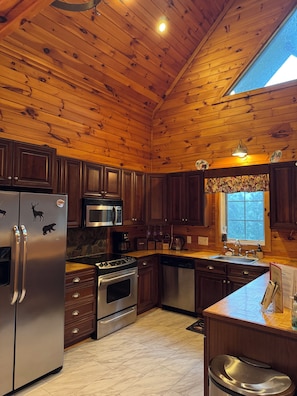 A wooden-paneled kitchen with stainless steel appliances, a stone backsplash, and a window with a view. - Beautiful cabin close to downtown Boone (Boone)