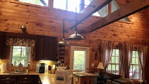 A wooden cabin interior with a kitchen area, a dining table, and a seating area. - Beautiful cabin close to downtown Boone (Boone)