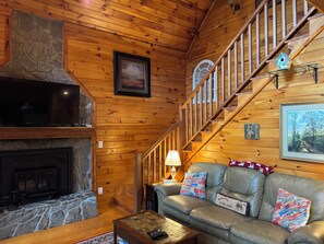 A cabin interior with a stone fireplace, leather sofa, wooden staircase, and a framed welcome sign. - Beautiful cabin close to downtown Boone (Boone)