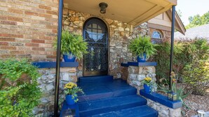 Une maison en pierre avec une porte bleue, des marches et des plantes en pot.