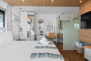 Une chambre d’hôtel moderne équipée d’un grand lit, d’un bureau, d’un miroir et d’une télévision.