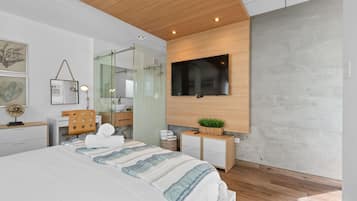 A modern bedroom with a large bed, a TV mounted on the wall, and a wooden ceiling.