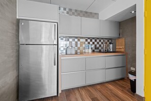 A modern kitchen with a stainless steel refrigerator, grey cabinets, a wooden countertop, and a checkered backsplash. - Beachfront | Ocean View | Wi-Fi | Self Check-In (Carolina)
