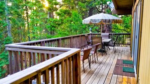 Une terrasse en bois avec une table et des chaises, entourée d’une végétation luxuriante.