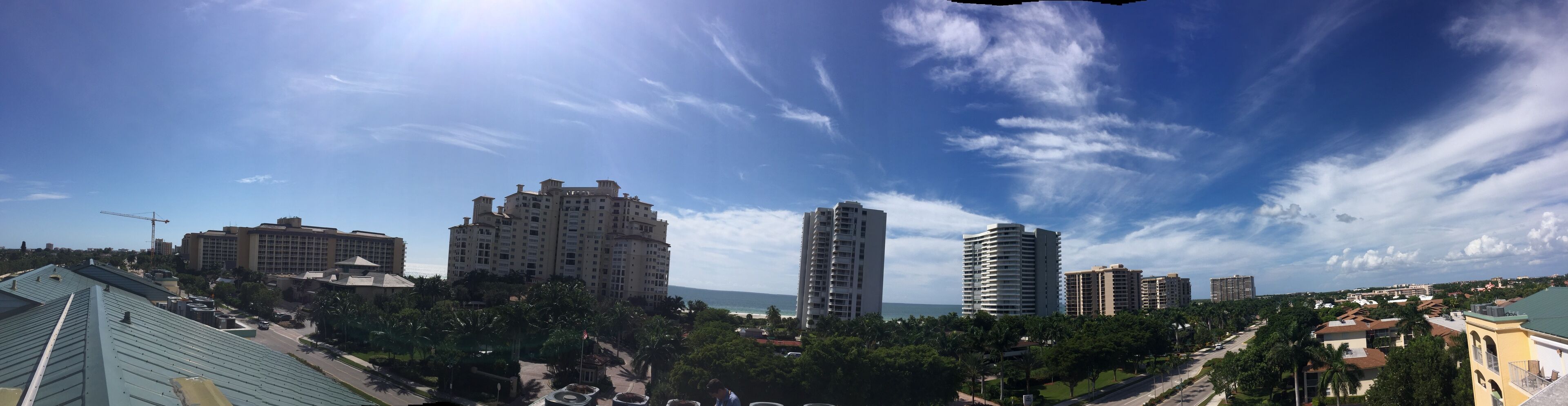 A cityscape with high-rise buildings, a clear sky, and a view of the ocean.