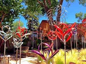 A garden with metal sculptures and a wooden bench.