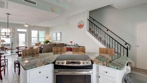 A kitchen with a central island, built-in oven, and a staircase leading to an upper level. - 🌞Oceanfront Rooftop getaway 🏖️Steps to sand 🐶Dog Friendly⚡️EV charger (North Topsail Beach)