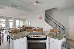 A kitchen with a central island, built-in oven, and a staircase leading to an upper level.