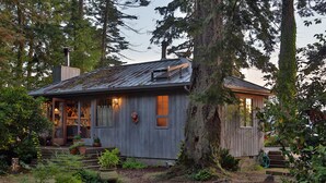 A rustic cabin with a wooden exterior, surrounded by trees and a garden.