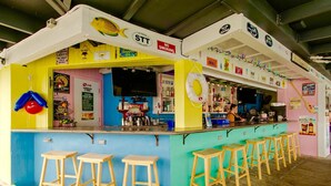 Un bar colorido con barra, taburetes y varios letreros.