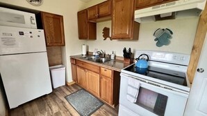 A kitchen with wooden cabinets, a white refrigerator, a stove, and a sink. - Denali Park 2 Bedroom Mom in Law (Healy)