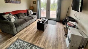 A living room with a sofa, coffee table, and a flat-screen TV. - Denali Park 2 Bedroom Mom in Law (Healy)