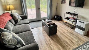 A living room with a sofa, a coffee table, a TV, and a heater. - Denali Park 2 Bedroom Mom in Law (Healy)