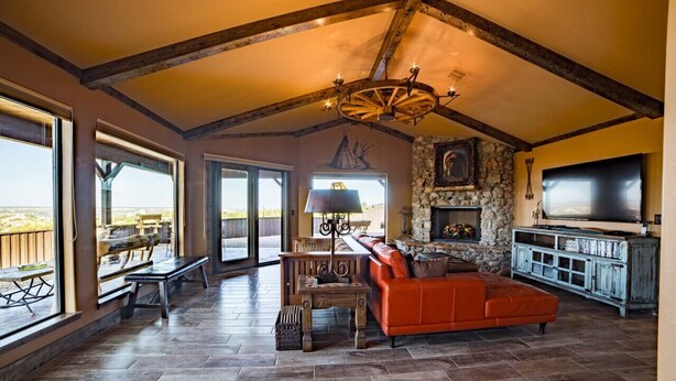 A spacious living room with a stone fireplace, a large TV, and a red leather sofa. - Comanche cabin on the west rim (Canyon)