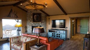 A cozy living room with a stone fireplace, a television, and a comfortable seating area. - Comanche cabin on the west rim (Canyon)