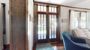 Une pièce avec une porte en bois, une chaise bleue et une fenêtre avec des stores.