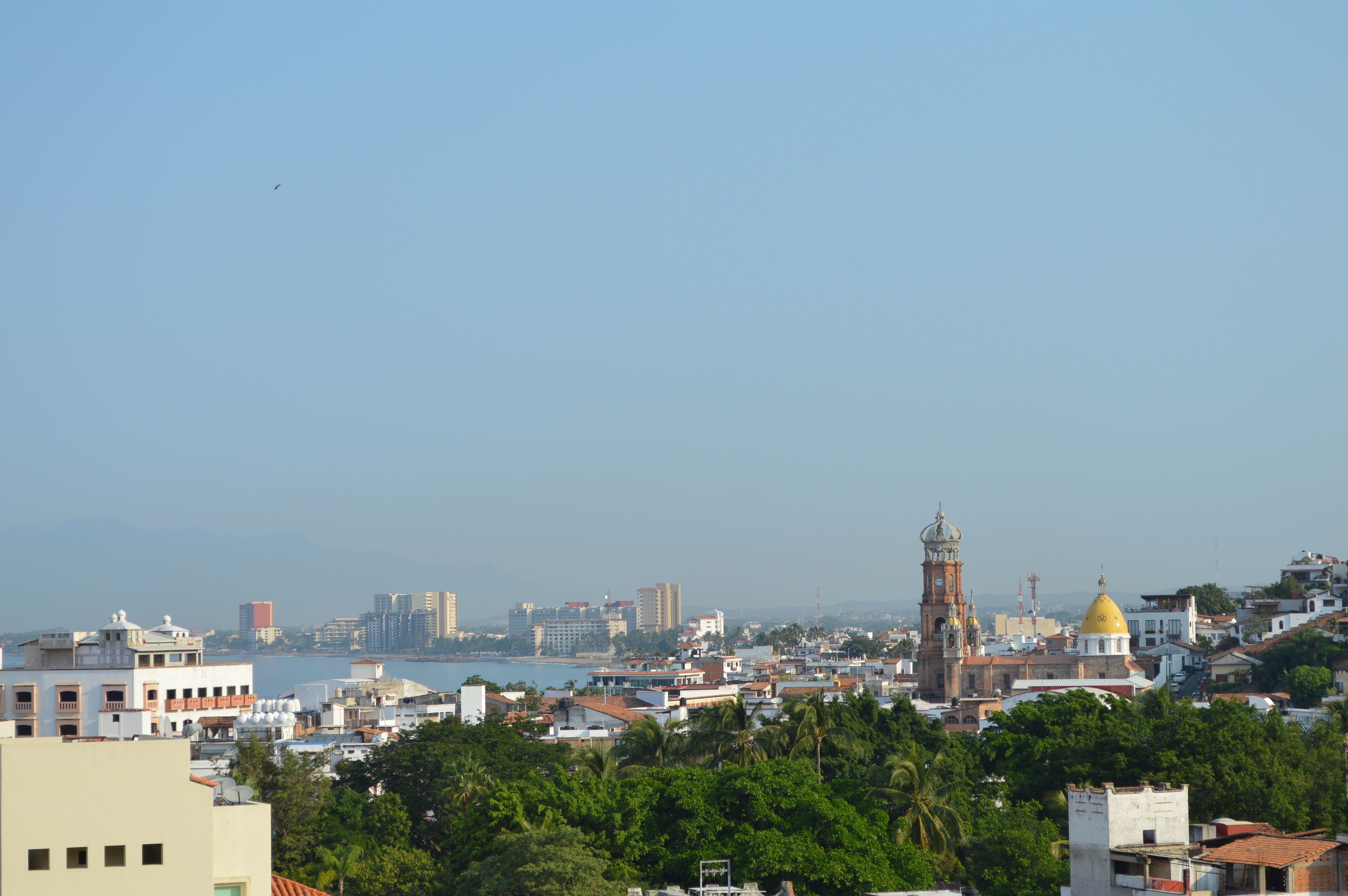 A coastal cityscape with a prominent clock tower and a golden dome.