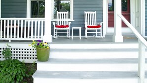 A porch with two white chairs and a green planter with flowers. - Historic 1870’s Spacious Home-2 Blocks From Belfast Village and the Bay (Belfast)