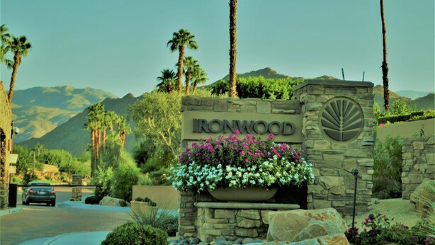 A stone sign with "IRONWOOD" and a leaf emblem, surrounded by a landscaped garden with flowers and rocks.