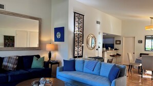 A living room with a sofa, coffee table, and a dining area with chairs and a table.