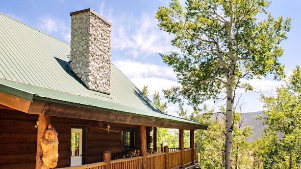 A log cabin with a stone chimney, wooden porch, and a view of a forested area. - Custom Log Cabin w/ MTN Views, 10 min. to fishing! (Basalt)