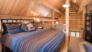 A cozy log cabin bedroom with a large bed, wooden ceiling beams, and a rustic door. - Custom Log Cabin w/ MTN Views, 10 min. to fishing! (Basalt)