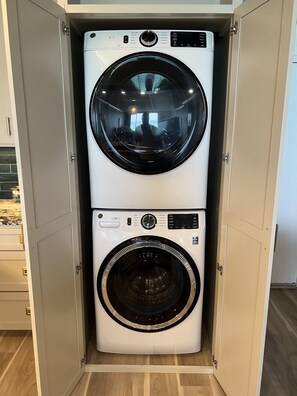 Ein kleiner, integrierter Waschraum mit zwei übereinander liegenden Waschmaschinen.