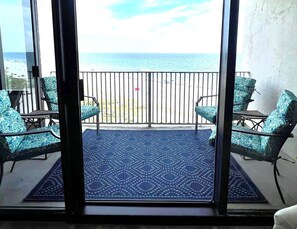 Un balcon donnant sur la plage, aménagé avec deux chaises et une petite table.