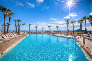 Une piscine d’un bleu éclatant, bordée de palmiers et dotée de chaises longues.