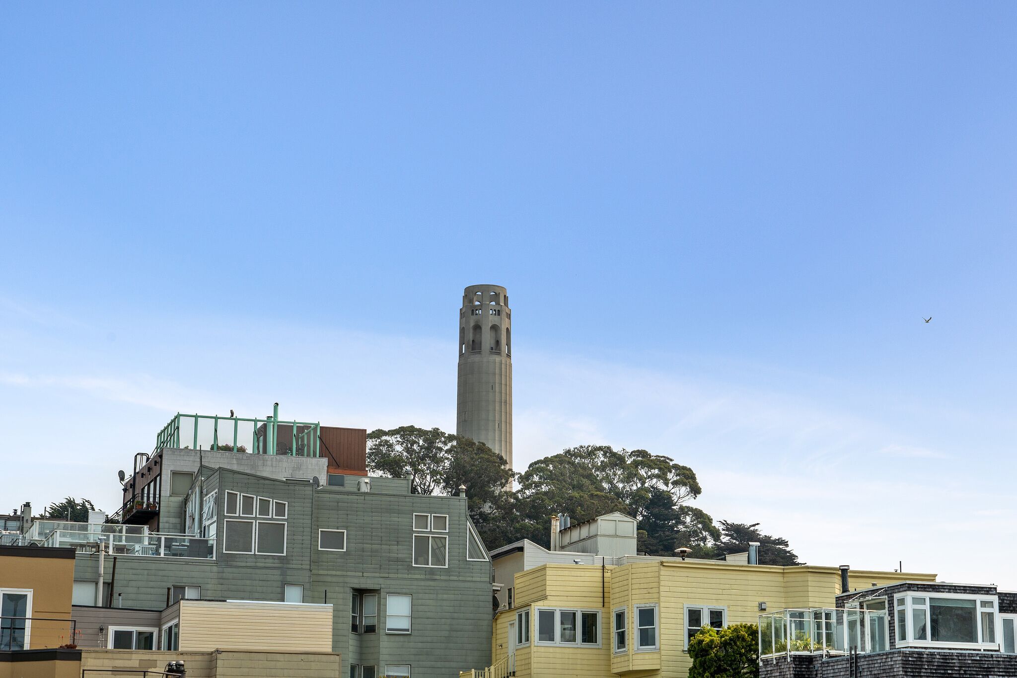 A modern building with a prominent tower, surrounded by other residential structures.