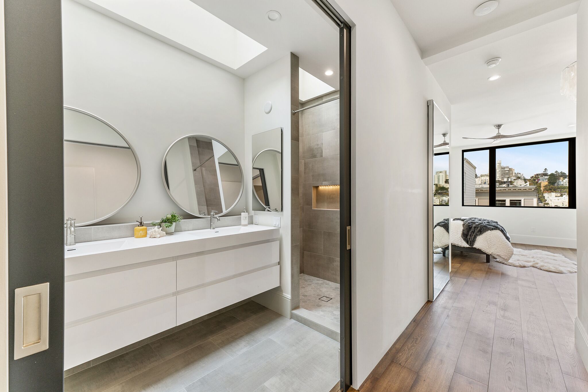 A modern bathroom with a skylight, a walk-in shower, and a large mirror.