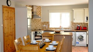 A kitchen with wooden cabinets, a sink, a stove, and a dining table set with white plates and bowls.