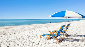 A beach with two blue and white beach chairs and an umbrella. - NEWLY RENOVATED/DIRECT FRONT/2 BEDROOM CONDO/INDOOR-OUTDOOR POOL/NEAR ATTRACTION (Orange Beach)