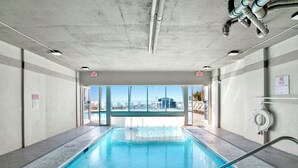 An indoor swimming pool with clear views of the cityscape through large windows. - NEWLY RENOVATED/DIRECT FRONT/2 BEDROOM CONDO/INDOOR-OUTDOOR POOL/NEAR ATTRACTION (Orange Beach)