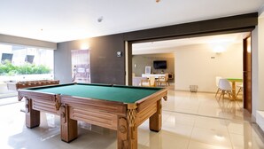 A pool table in a well-lit room with a modern design, a dining area with chairs, and a kitchen in the background. - Luxury 2BDR in Miraflores - UP1, A/C, Soundproof windows, Pool, BBQ (Lima)