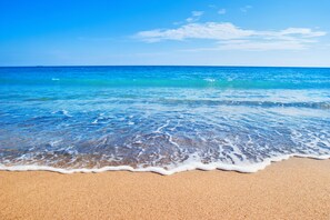 Una playa con agua azul cristalina y una orilla arenosa.