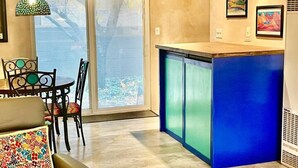 Una cocina moderna con encimera azul y comedor con mesa y sillas.