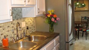 Una cocina con armarios blancos, un refrigerador de acero inoxidable y un lavamanos doble.