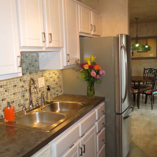 A kitchen with white cabinets, a stainless steel refrigerator, and a double sink.