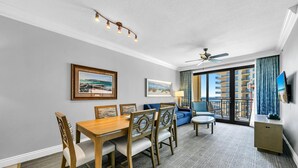 Et hotelværelse med spiseplads, en balkon med udsigt og en loftsvifte.