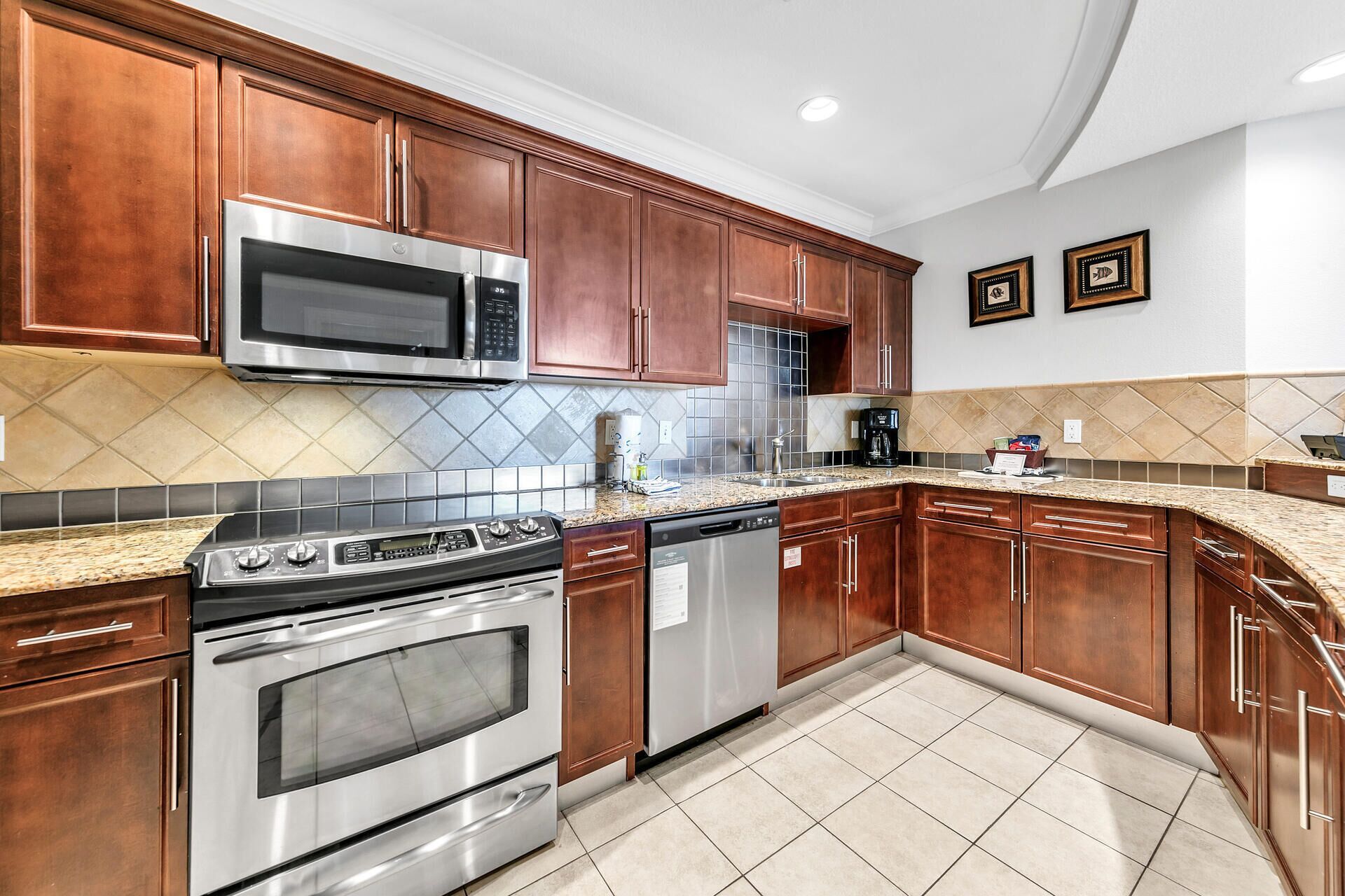 A kitchen with wooden cabinets, stainless steel appliances, a tiled backsplash, and granite countertops.