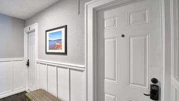A hallway with a bench, a door with a keypad lock, and a framed picture on the wall.