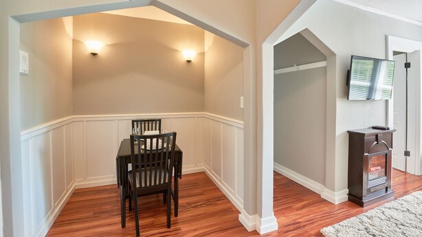 A dining area with a wooden table and chairs, a built-in bench along the wall, and a fireplace with a TV mounted above it.
