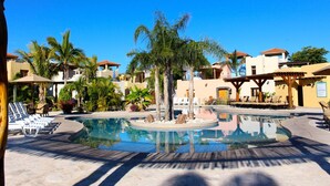 A resort pool area with lounge chairs and palm trees. - Charming Casa by the picturesque Sea of Cortes (Loreto)