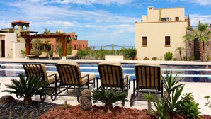 A pool area with lounge chairs, a pergola, and a view of a mountain and ocean. - Charming Casa by the picturesque Sea of Cortes (Loreto)