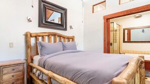 A wooden bed with a headboard, a bedside table, a mirror, and a framed picture on the wall.